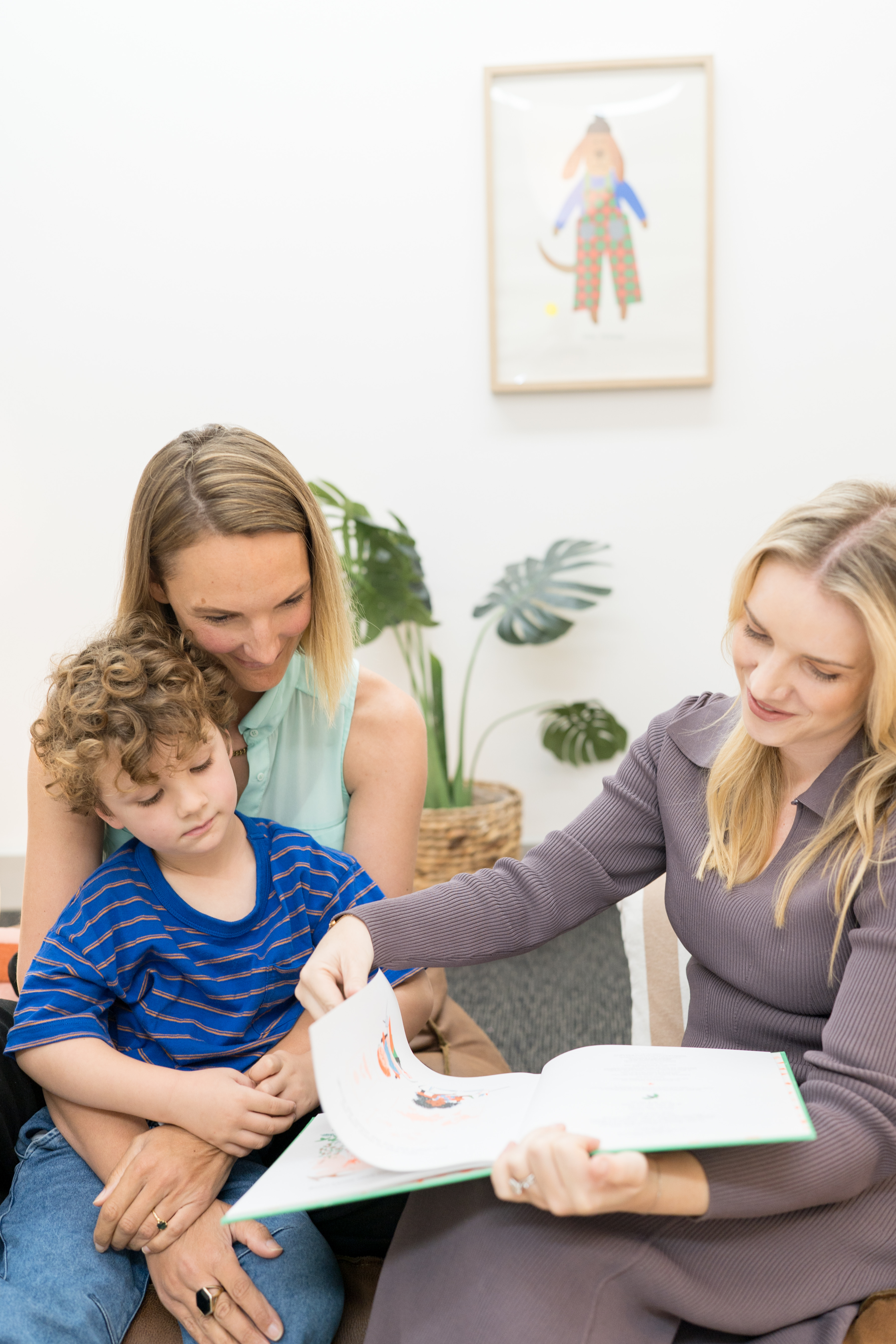 A speech pathologist sharing a picture book with a young child, both smiling as they read together
